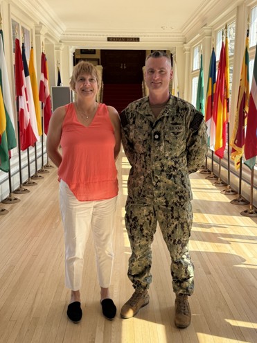 Two people in front of a hallway of flags